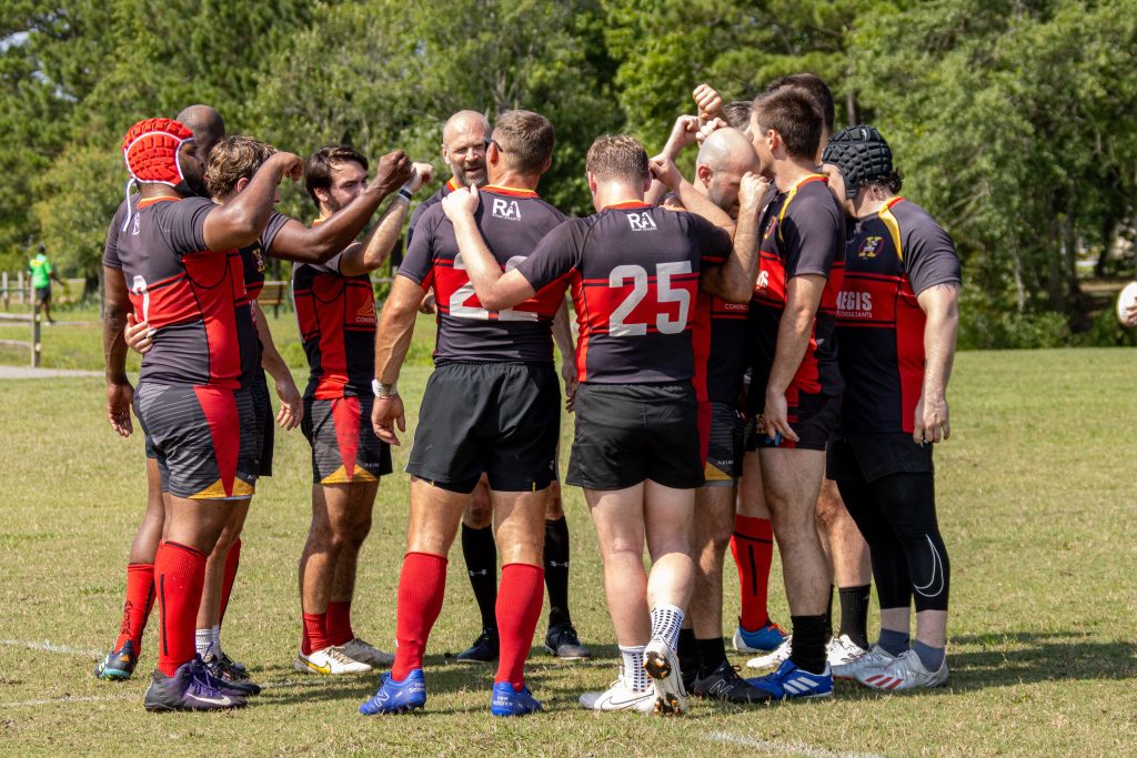 Rugby team huddled on the field post game to conclude the match.