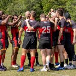 Rugby team huddled on the field post game to conclude the match.